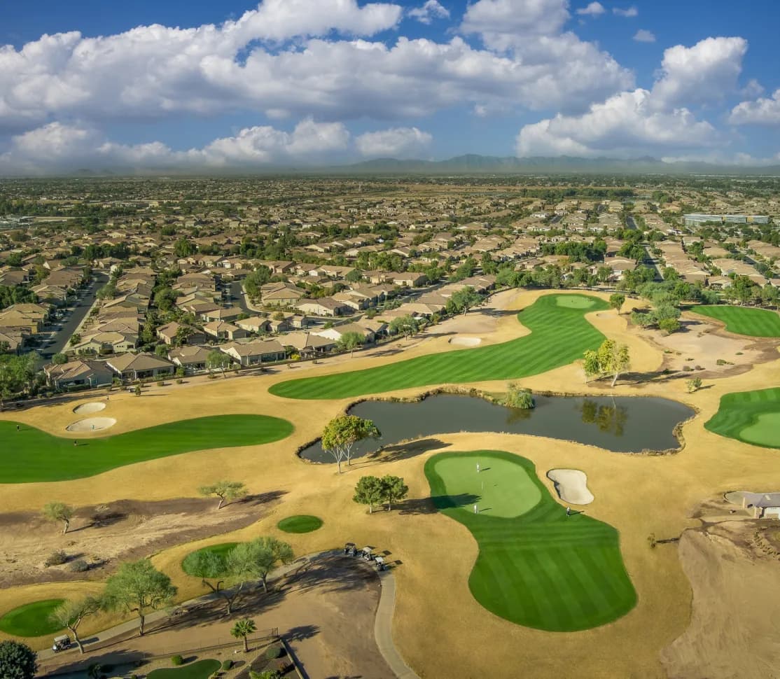 Aerial view of golf course with sprawling suburban neighborhoods in the background