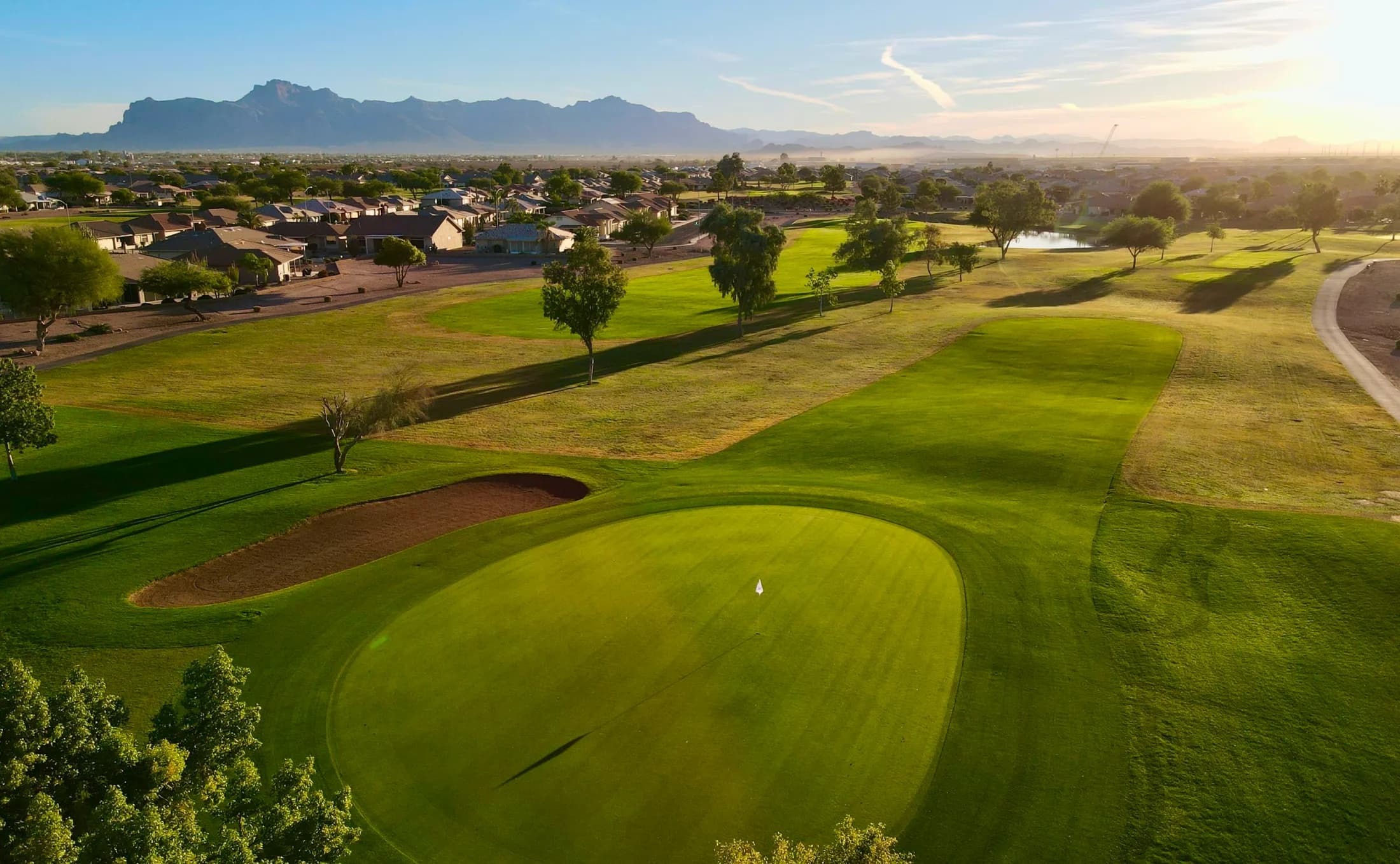 Aerial view of Sunland Spring Golf Course with suburban homes and mountains in the background
